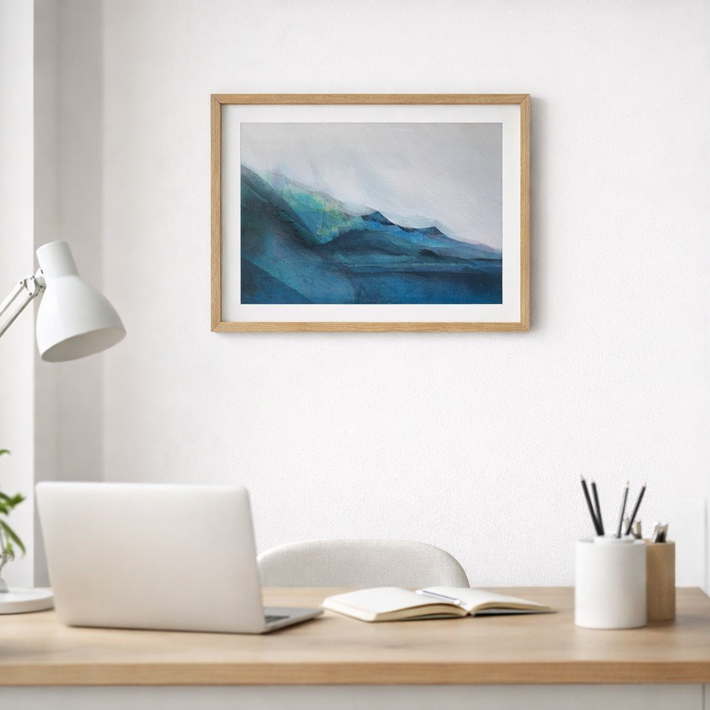 Framed abstract painting of a mountain landscape above a desk with a laptop and stationery.